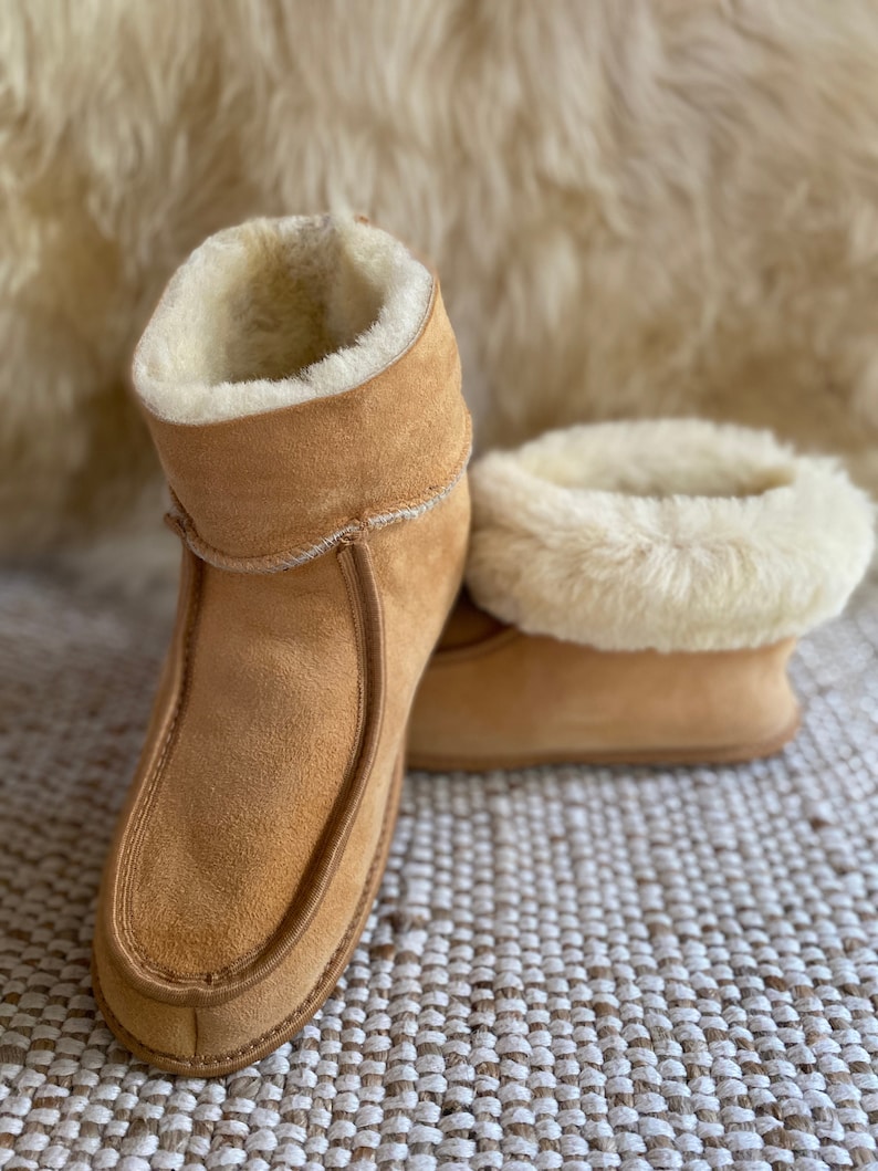 Puede incluir: Un par de zapatillas de ante marr&oacute;n con forro de piel de oveja blanca. Las zapatillas tienen un pu&ntilde;o abatible y una punta puntiaguda.