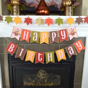 May include: A brown, yellow, red, and green banner with the words "Happy Birthday" in pink letters. The banner is decorated with images of turkeys. The banner is hanging above a fireplace.