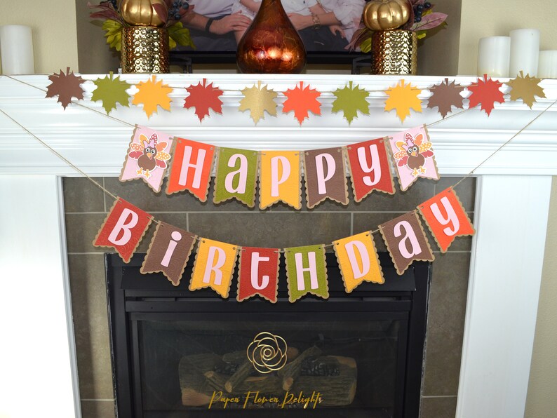 May include: A brown, yellow, red, and green banner with the words "Happy Birthday" in pink letters. The banner is decorated with images of turkeys. The banner is hanging above a fireplace.