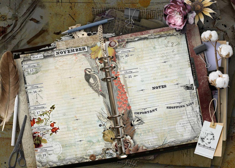 An open ring-bound planner with cream-colored pages featuring a November calendar layout. The pages include illustrations of a bird, berries, and floral elements, with printed text labels for days, notes, important, and shopping list.