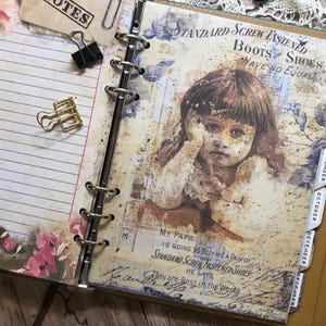 May include: Open journal with lined pages, binder rings, and a vintage-style illustration of a child. The journal features a floral design, binder clips, and monthly tabs. The illustration includes text that reads "STANDARD SCREW FASTENED BOOTS SHOES HAVE NO EQUAL."