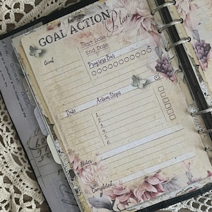 May include: A vintage-style planner page with the words "GOAL ACTION Plan" at the top. The page features sections for goals, dates, progress, and action steps. Floral and butterfly accents add a decorative touch to the design.
