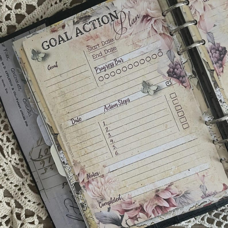 May include: A vintage-style planner page with the words "GOAL ACTION Plan" at the top. The page features sections for goals, dates, progress, and action steps. Floral and butterfly accents add a decorative touch to the design.