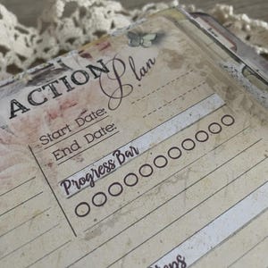 May include: Close-up of a vintage-style planner page with the words "ACTION Plan" in elegant script. The page features sections for start and end dates, and a "Progress Bar" with circles. The background has a floral design.