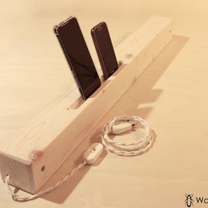 May include: A wooden phone charging station with two slots for phones and a white cord with a switch.