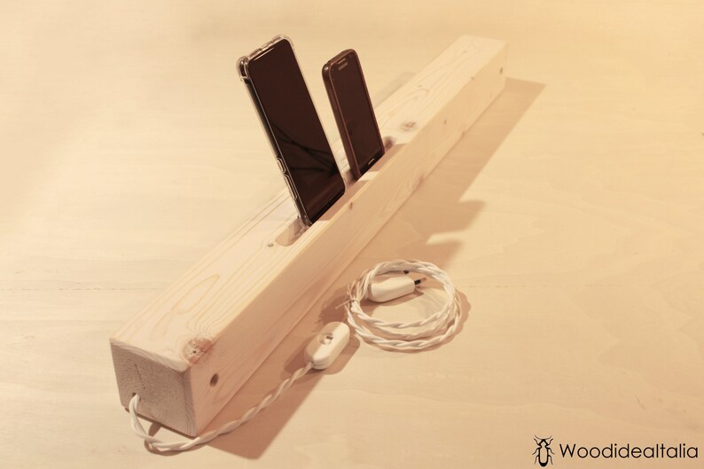 May include: A wooden phone charging station with two slots for phones and a white cord with a switch.