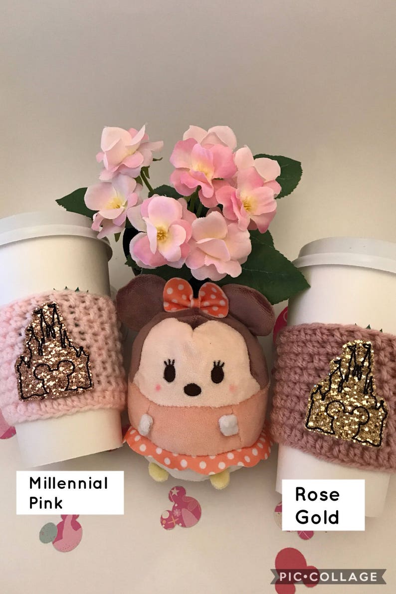 May include: Two pink and rose gold coffee cup sleeves with a gold glitter castle design. The sleeves are on white coffee cups. A pink and white plush toy is in the center of the image.