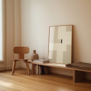 May include: A wooden bench with a brown cushion, a wooden chair, a vase, and a framed abstract art print with geometric shapes in beige and white. The bench has a shelf underneath with books stacked on it.
