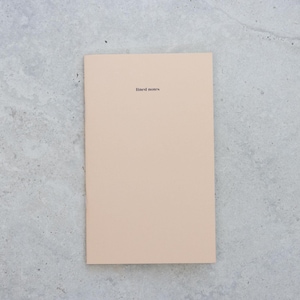 May include: A rectangular notebook with a solid light beige cover. The words "lined notes" are printed in a small, black, sans-serif font centered near the top of the front cover. The notebook has a clean, simple design with a smooth, matte finish.