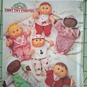 May include: A Butterick 3107 sewing pattern envelope for Cabbage Patch Kids Teeny Tiny Preemies dolls. The cover features five dolls in various outfits, including a sailor suit, a red jacket, and patterned sleepers, labeled with letters B, C, D, E, and P.