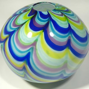 May include: A round glass vase with a swirling pattern of blue, green, purple, and white.