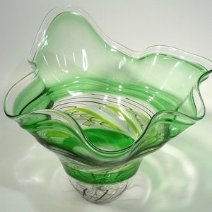 May include: A green glass bowl with a wavy rim and a swirl design in the bottom. The bowl is clear and has a textured surface.
