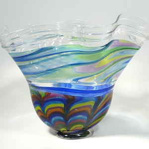 May include: A clear glass vase with a ruffled top and a colourful, swirling pattern in blue, green, yellow, orange, and red.