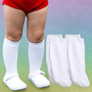 May include: A young girl wearing a red and white short romper with a colorful fish print, white knee-high socks, and white shoes. She is wearing a yellow headband with a bow and a beaded necklace. Three pairs of white knee-high socks are in the foreground.