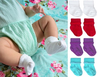 Op de afbeelding: Een set van zes paar babysokken in wit, rood, paars en turquoise. Elk paar heeft een gerimpelde rand aan de bovenkant.