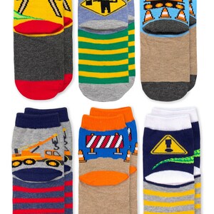 Puede incluir: Seis pares de calcetines tobilleros con gr&aacute;ficos de tem&aacute;tica de construcci&oacute;n. Los dise&ntilde;os incluyen barreras viales amarillas, se&ntilde;ales de tr&aacute;fico, excavadoras, gr&uacute;as y patrones de rayas en colores rojo, amarillo, azul, verde, naranja, gris, marr&oacute;n y blanco.