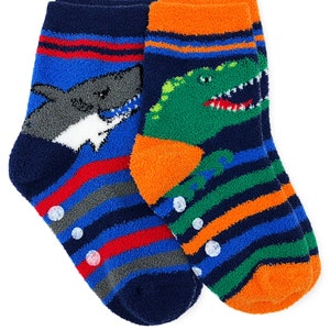 May include: A pair of blue, orange, green, and red striped fuzzy socks with a shark and dinosaur graphic. The socks have non-slip dots on the bottom.