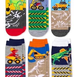Puede incluir: Un conjunto de seis pares de calcetines tobilleros con coloridos estampados gr&aacute;ficos de dinosaurios, veh&iacute;culos de construcci&oacute;n y esqueletos f&oacute;siles. Los dise&ntilde;os incluyen fondos amarillos, azules, grises y azul marino con rayas.
