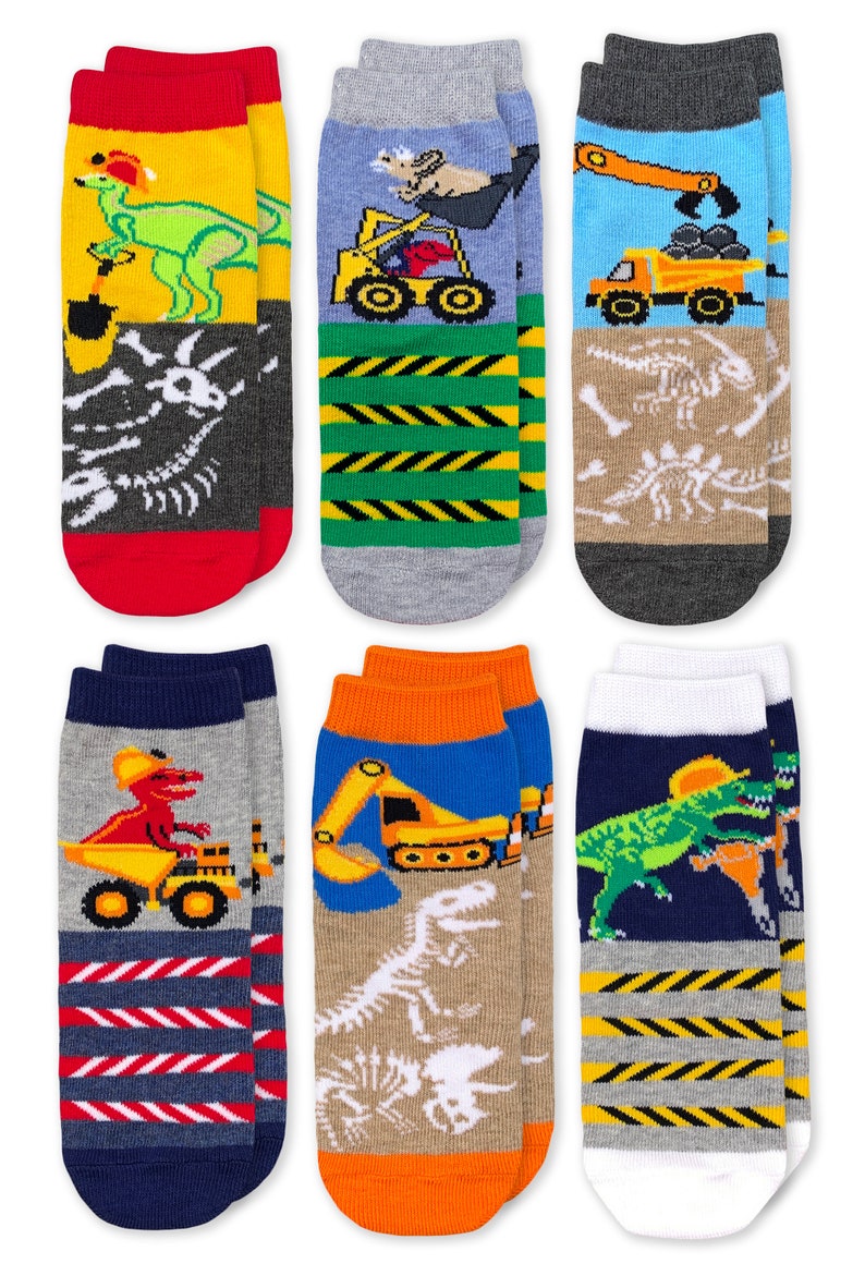 Puede incluir: Un conjunto de seis pares de calcetines tobilleros con coloridos estampados gr&aacute;ficos de dinosaurios, veh&iacute;culos de construcci&oacute;n y esqueletos f&oacute;siles. Los dise&ntilde;os incluyen fondos amarillos, azules, grises y azul marino con rayas.