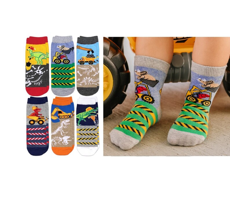 Puede incluir: Un conjunto de seis pares de calcetines con varios dise&ntilde;os coloridos de veh&iacute;culos de construcci&oacute;n y dinosaurios. Los patrones incluyen excavadoras amarillas, camiones volquete y dinosaurios verdes, junto con rayas de peligro y f&oacute;siles.