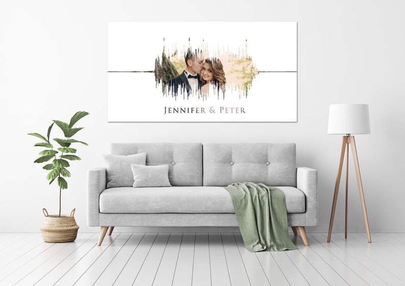 May include: A white canvas print with a sound wave design featuring a photo of a couple. The sound wave is made up of vertical lines in shades of brown and green. The text "Jennifer & Peter" is printed below the sound wave.