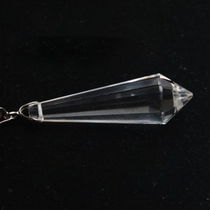 May include: A clear crystal pendulum with a pointed tip and a silver chain.