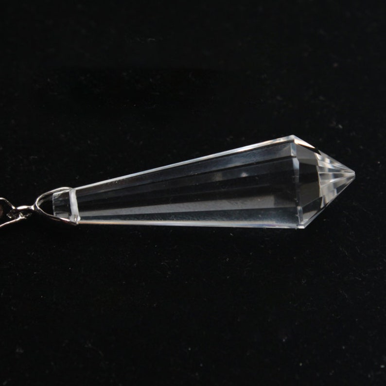 May include: A clear crystal pendulum with a pointed tip and a silver chain.