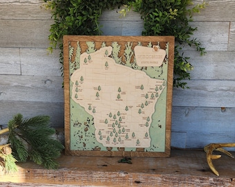 May include: A wooden map of Wisconsin state parks with the names of each park labeled. The map is framed in a brown wood frame and has a green background.