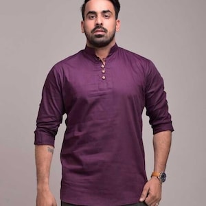 Pu&ograve; includere: Una camicia a maniche lunghe viola scuro con colletto alla coreana e tre bottoni in legno. La camicia &egrave; realizzata in un tessuto a tinta unita e ha una vestibilit&agrave; rilassata. Le maniche sono arrotolate fino ai gomiti.