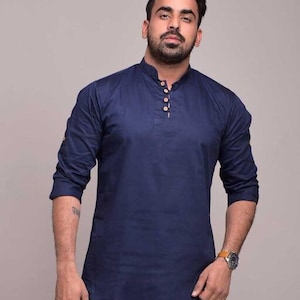 Pu&ograve; includere: Una camicia blu navy a maniche lunghe con colletto alla coreana e tre bottoni in legno. La camicia ha una vestibilit&agrave; rilassata ed &egrave; realizzata in un tessuto morbido e traspirante. Le maniche sono arrotolate fino ai gomiti.