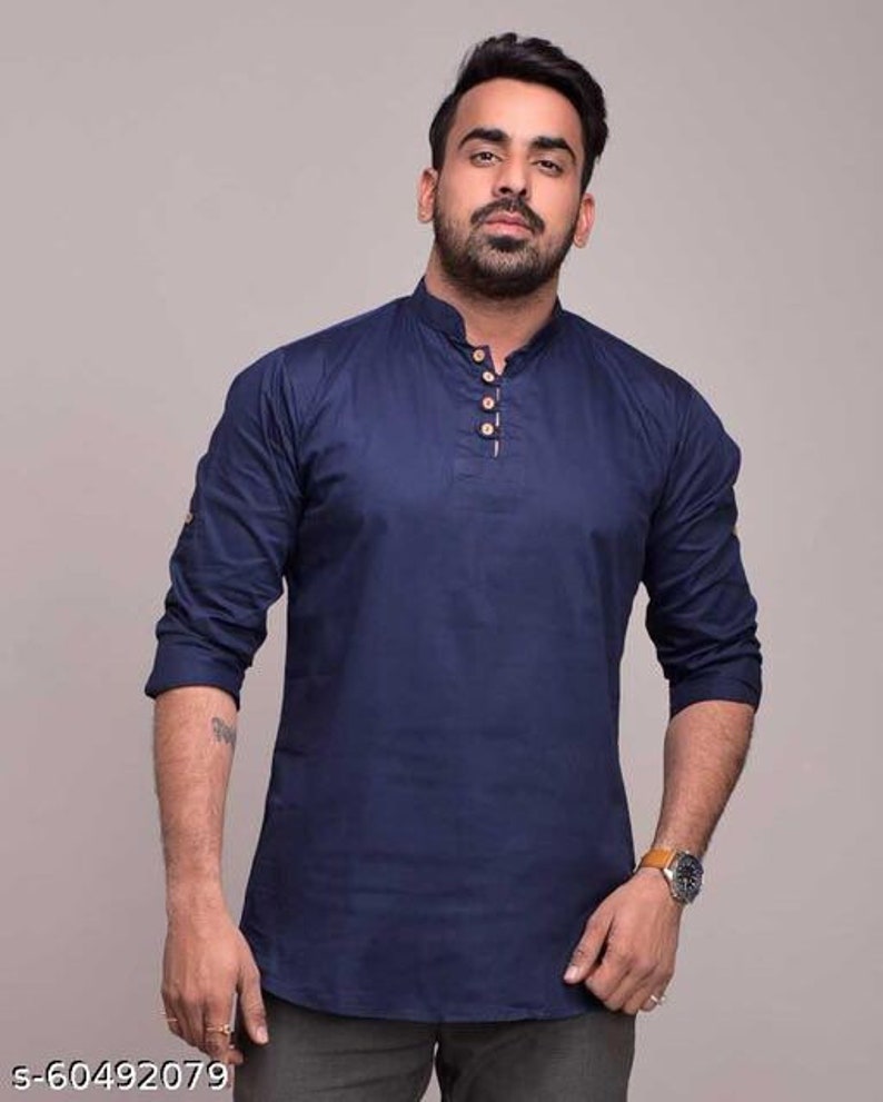 Pu&ograve; includere: Una camicia blu navy a maniche lunghe con colletto alla coreana e tre bottoni in legno. La camicia ha una vestibilit&agrave; rilassata ed &egrave; realizzata in un tessuto morbido e traspirante. Le maniche sono arrotolate fino ai gomiti.