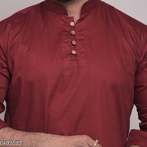 Pu&ograve; includere: Una camicia kurta color bordeaux con colletto alla coreana e maniche lunghe. La camicia presenta una paramontura con bottoni con quattro bottoni in legno. Il tessuto sembra essere un materiale morbido e tessuto. Il testo "s-60492082" &egrave; nell'angolo in basso a sinistra.