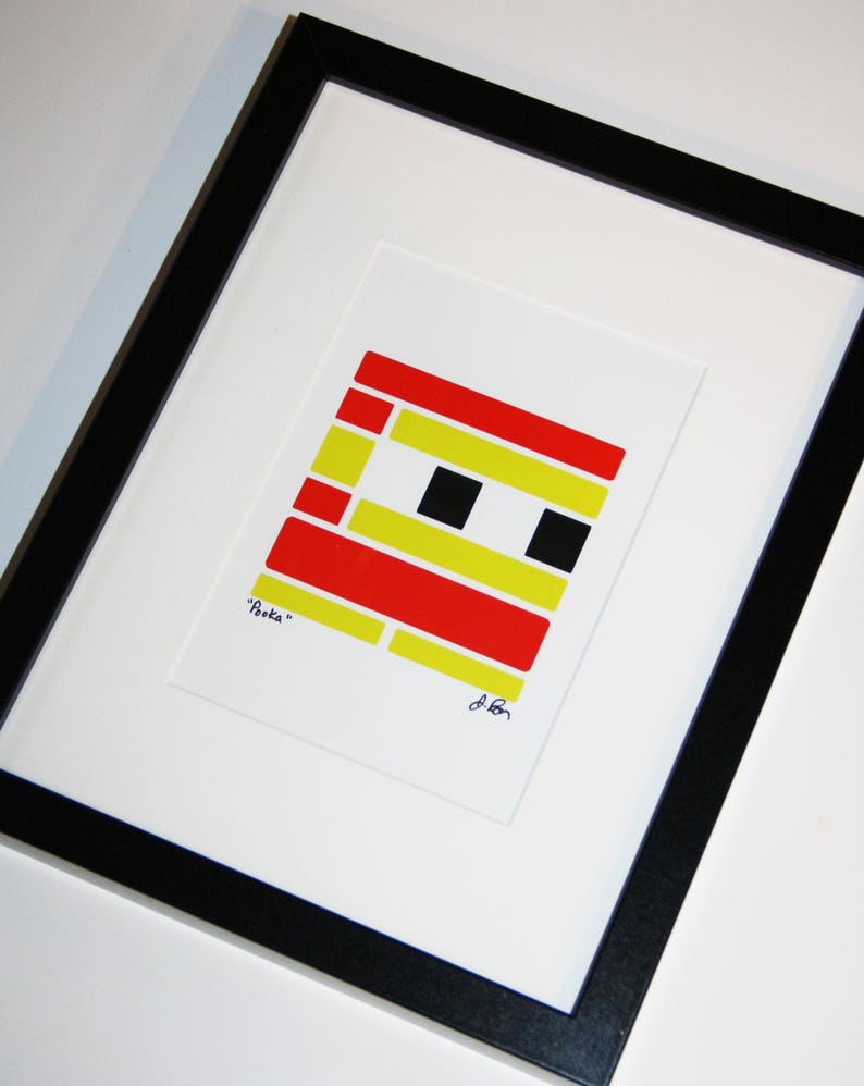 K&ouml;nnte beinhalten: Gerahmter Kunstdruck mit einem geometrischen Design in Rot, Gelb und Schwarz. Das Kunstwerk mit dem Titel "Pooka" befindet sich vor einem wei&szlig;en Hintergrund in einem schwarzen Rahmen. Die Signatur des K&uuml;nstlers ist sichtbar.