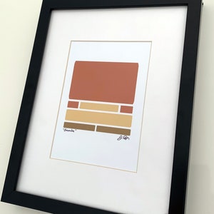 May include: A framed abstract art print with a geometric design in shades of brown, beige, and orange. The print is titled "Sombre" and signed by the artist.