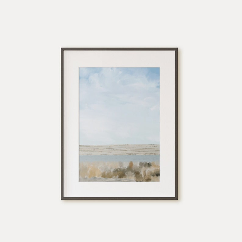 May include: A framed watercolor painting of a landscape with a blue sky, white clouds, and a body of water in the foreground. The water is surrounded by brown and green brush.