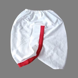 Puede incluir: Pantal&oacute;n blanco de algod&oacute;n con ribete rojo y blanco a rayas alrededor de las piernas.