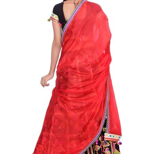 Puede incluir: Un vestido rojo y negro con bordados y adornos coloridos. El vestido tiene una falda larga y un corpi&ntilde;o ajustado. La mujer lleva un dupatta rojo sobre la cabeza y los hombros.