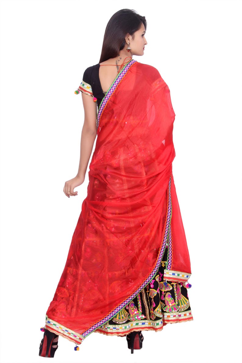 Puede incluir: Un vestido rojo y negro con bordados y adornos coloridos. El vestido tiene una falda larga y un corpi&ntilde;o ajustado. La mujer lleva un dupatta rojo sobre la cabeza y los hombros.