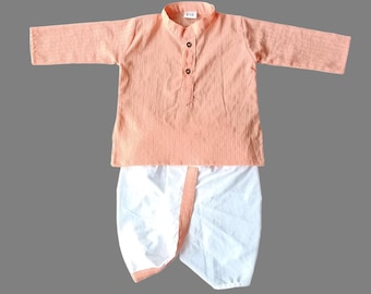 Puede incluir: Un kurta de color melocotón con un dhoti blanco. El kurta tiene un cierre de botón en el cuello y un patrón a rayas. El dhoti es blanco con un ribete melocotón.