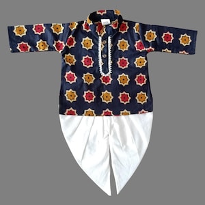 May include: A blue and white kurta pajama set for a child. The kurta has a geometric pattern with red, yellow, and white accents. The pajama is white and has a dhoti style.