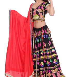 Puede incluir: Un vestido de estilo indio negro y rojo con bordados coloridos y trabajo de espejo. El vestido tiene una falda larga y una blusa corta con un dupatta rojo.
