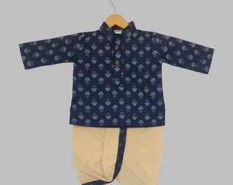 May include: A navy blue kurta and dhoti set for children. The kurta features a floral pattern and a mandarin collar. The dhoti is a light beige color. The outfit is displayed on a wooden hanger.