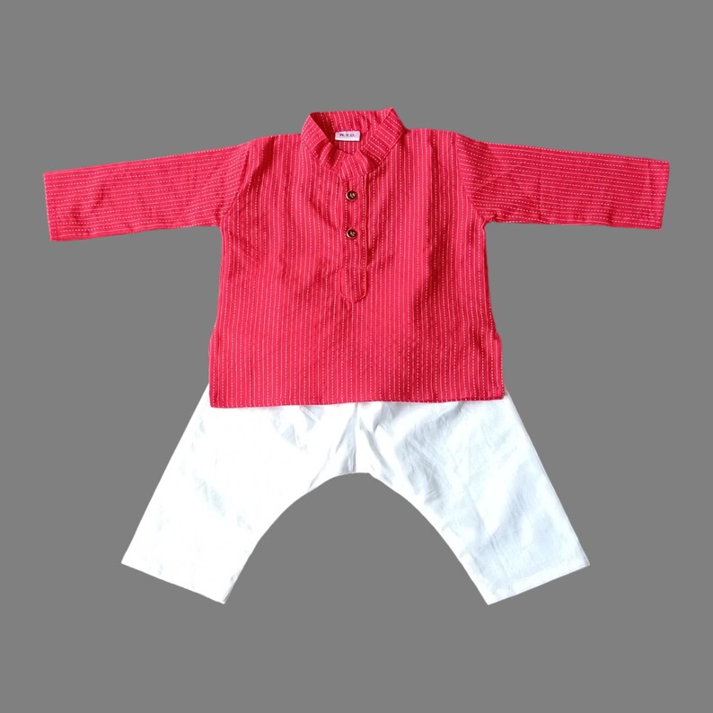 Puede incluir: Un kurta de rayas rojas y blancas con cierre de bot&oacute;n blanco y pantalones blancos a juego. El atuendo es ropa tradicional india para ni&ntilde;os.