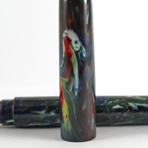 May include: Close-up of a colorful pen cap with a swirling pattern of red, yellow, blue, and white. The pen cap is made of a dark, mottled material.