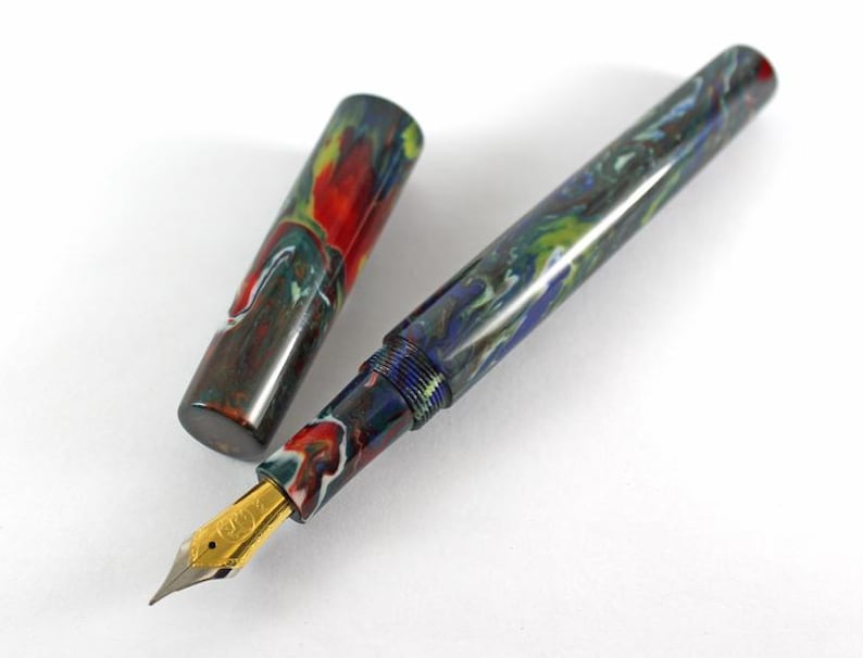 May include: A fountain pen with a colorful, marbled, blue, green, and red resin body and a gold nib. The pen is open and the cap is lying next to it.
