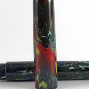 May include: A close-up of a red, green, and blue marbled pen cap. The cap is made of a smooth, glossy material.