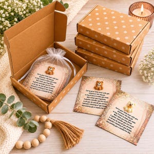 May include: A set of brown cardboard gift boxes with white polka dots, each containing a small card with a miniature teddy bear figurine and the printed text: Carry your little bear with you wherever life may go. A tiny friend to make you smile.