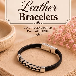 a black leather bracelet with silver metal accents, placed on a beige surface. The background includes a small floral arrangement and a beige bowl.