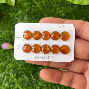 May include: A close-up of eight orange gemstone cabochons, each measuring 10mm in diameter, arranged in two rows of four on a white card with the text "S29" and "10x10MM".