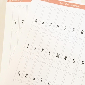 May include: Printable alphabet and number banner flags. The flags are white with black outlines and letters. The letters are A through Z and the number is 1.